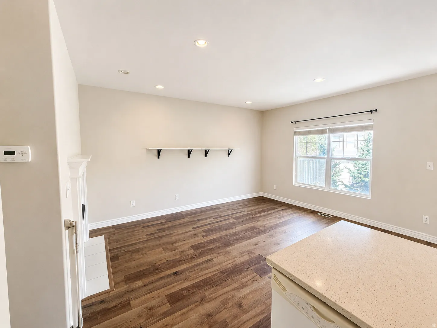 Spacious room featuring wood-finish flooring, recessed lighting, and a prominent window