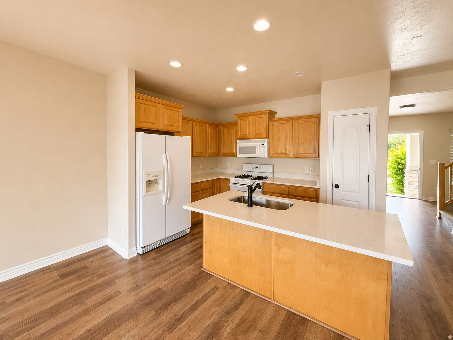 Modern kitchen with wood-finish flooring, recessed lighting, light-toned cabinetry, and white countertops
