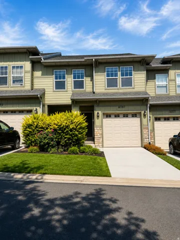 Contemporary townhouse exterior featuring a neutral green siding, a two-car garage, and a concrete driveway