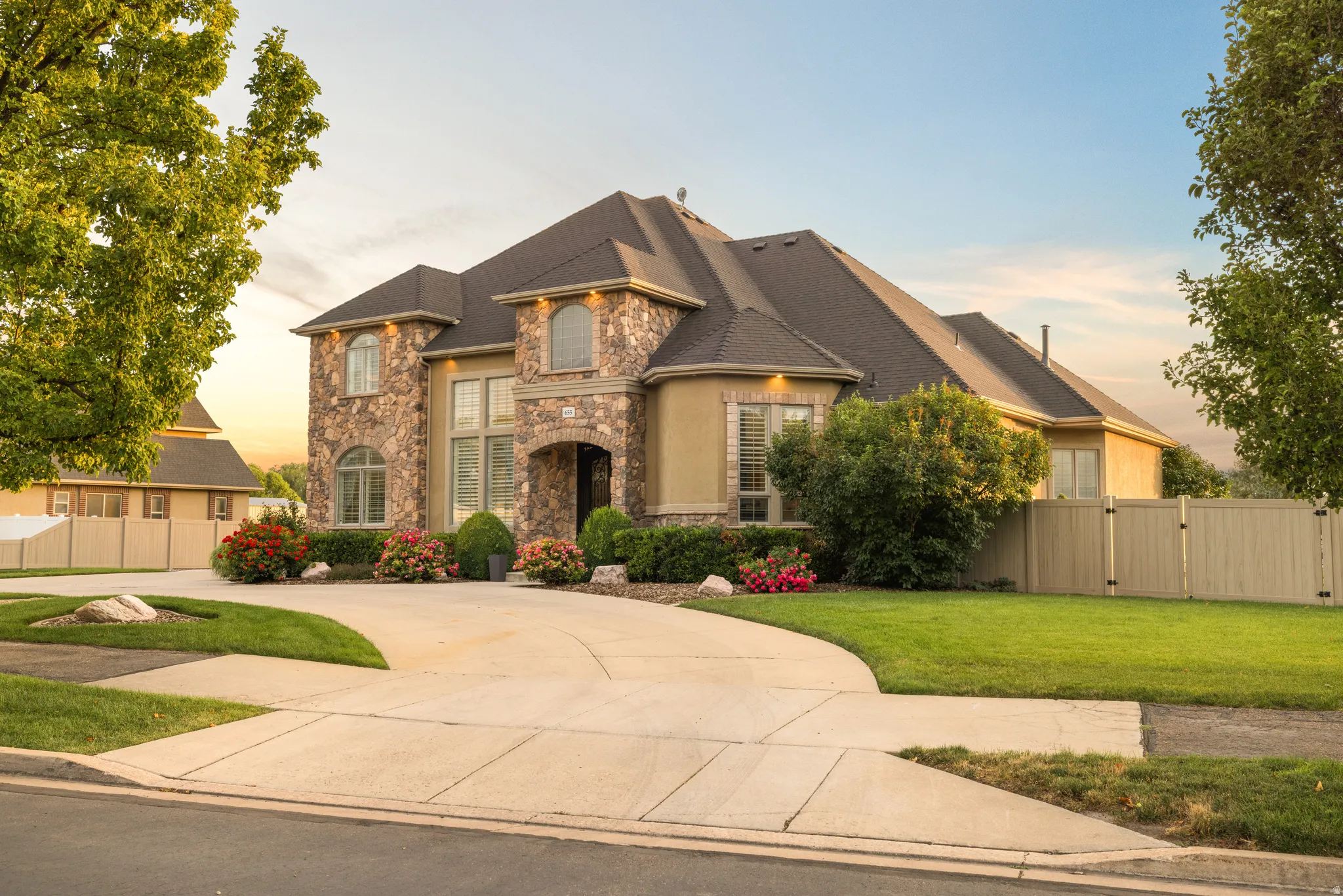 Stately two-story residence featuring stone and stucco exterior, arched entry, and a multi-level roofline