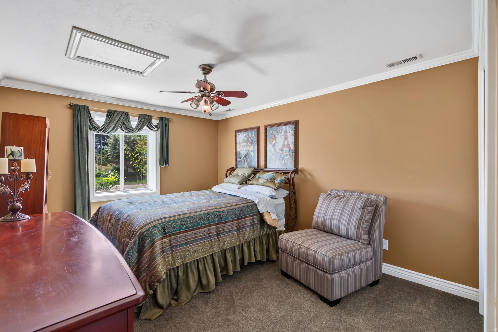 Carpeted room with a ceiling fan light fixture, overhead skylight, and white crown molding