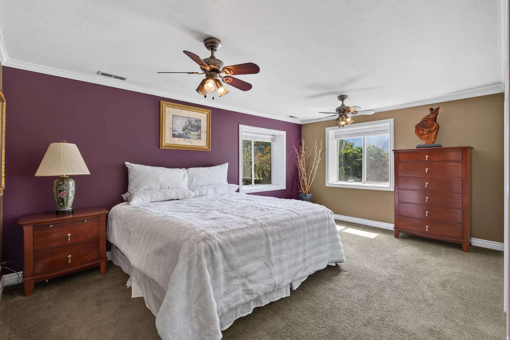 Spacious room featuring two windows, crown molding, and two ceiling fans with integrated lighting