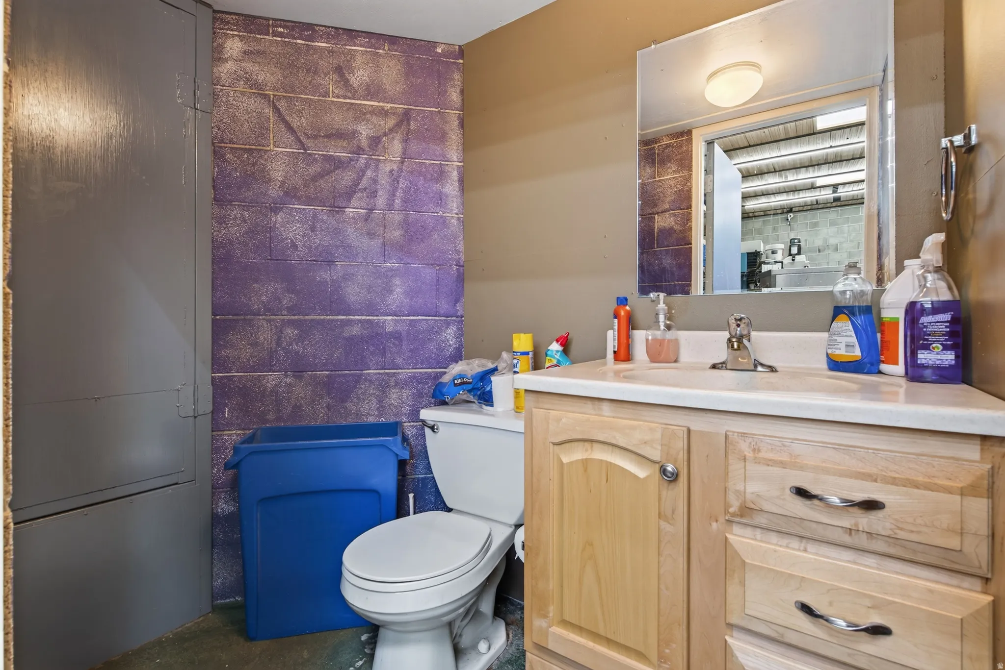 Bathroom featuring a wood-finish vanity with a light-toned countertop, a rectangular sink, and a wall-mounted mirror