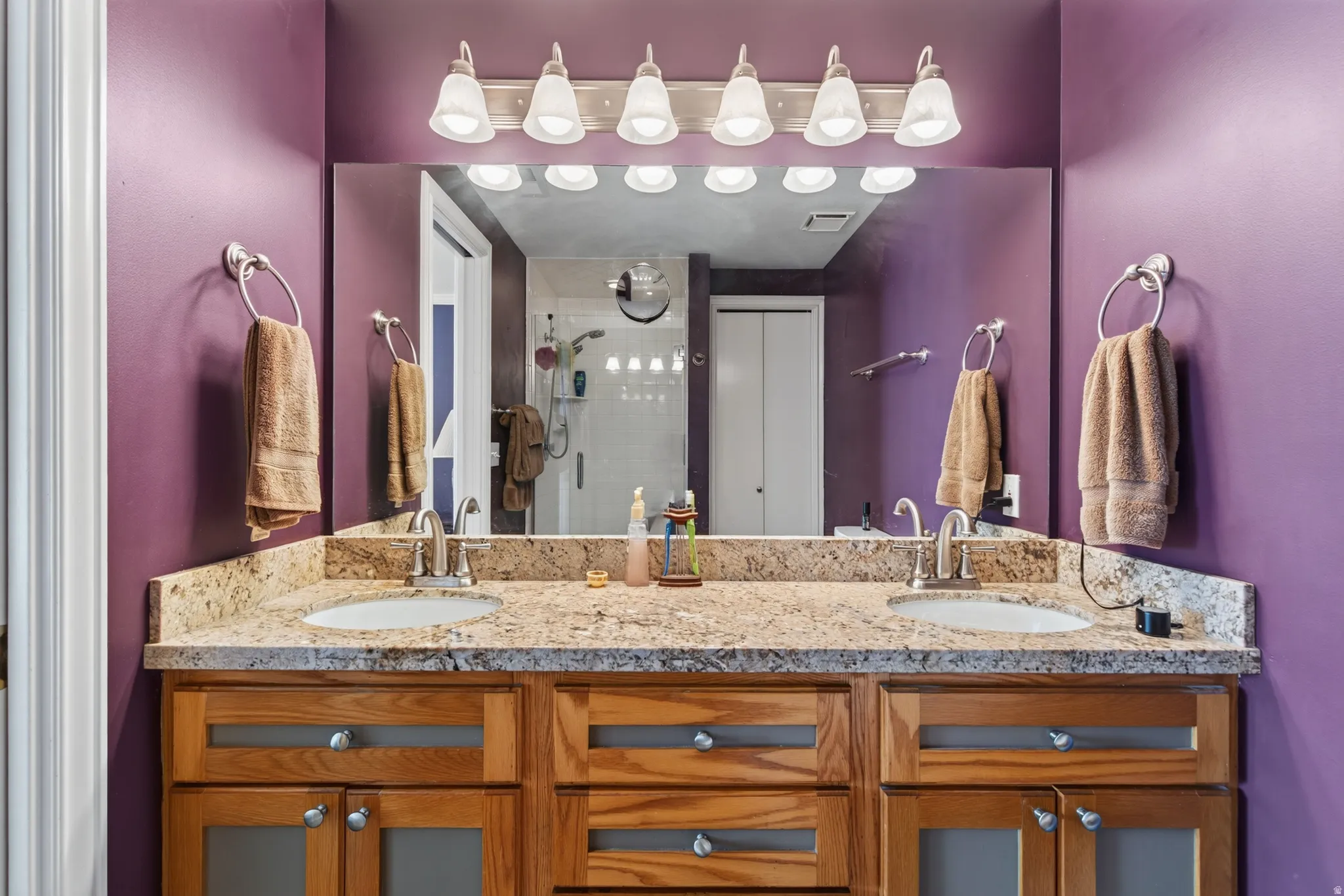Dual vanity with a stone-finish countertop, undermount sinks, and ample storage within the wood-finish cabinetry