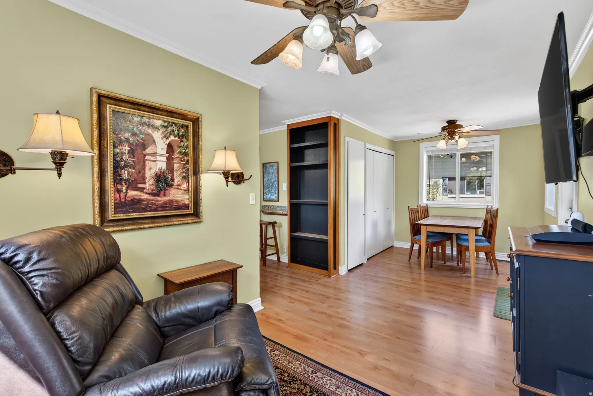 Open concept living area featuring wood-finish flooring, two ceiling fans, and built-in shelving