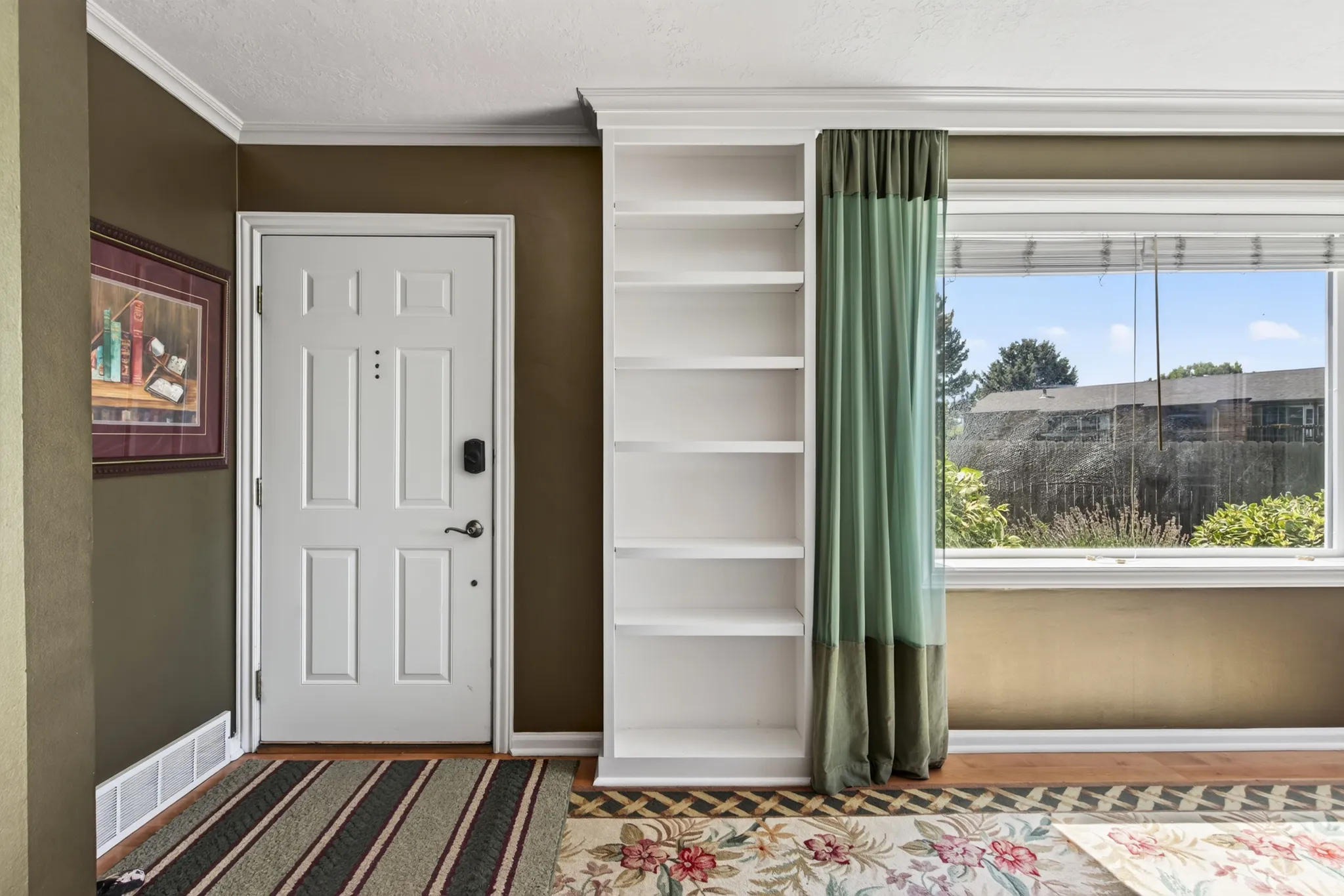 Entryway featuring a paneled door, built-in shelving, crown molding, and a large window
