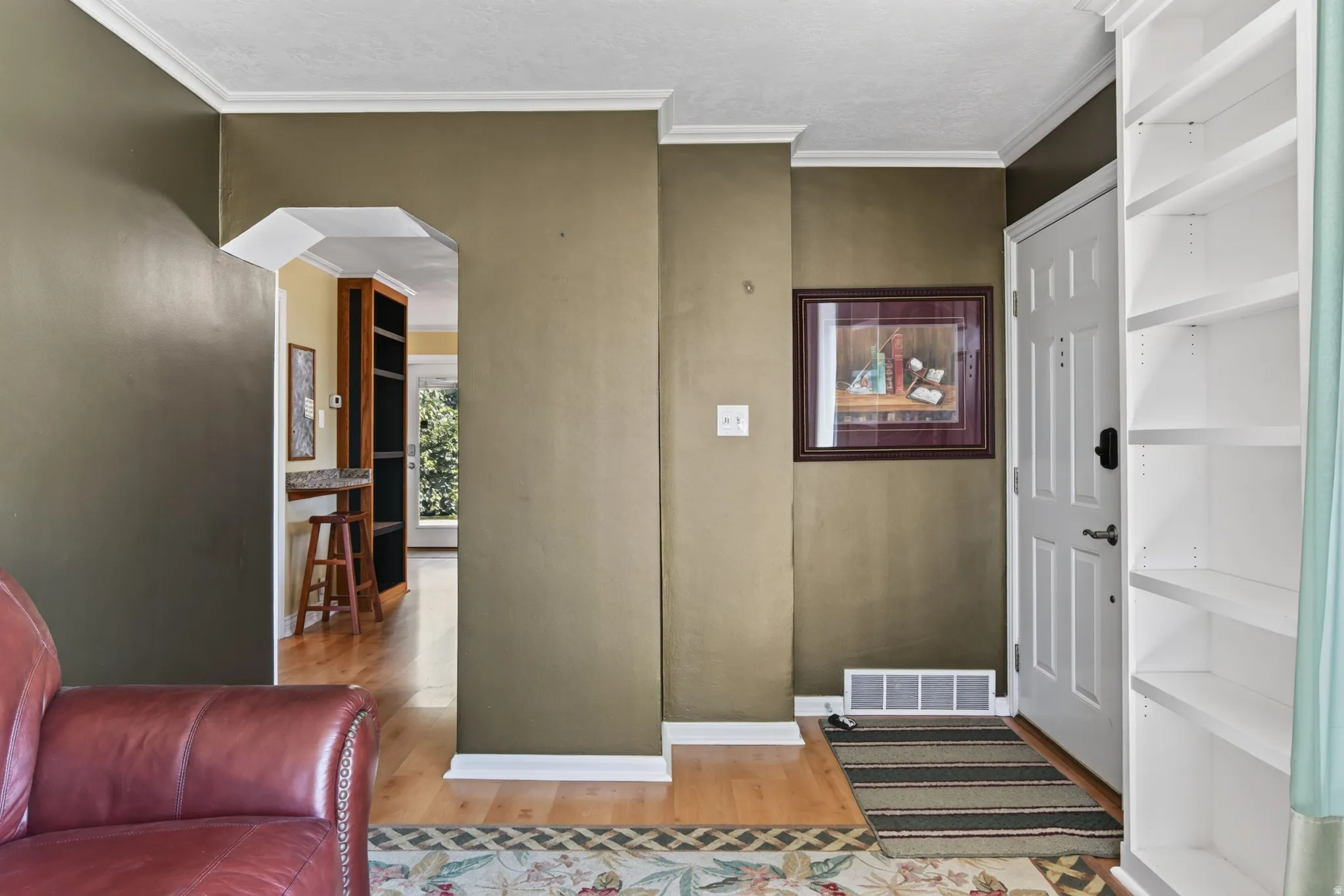 Entryway featuring wood-finish flooring, white trim, and a paneled door