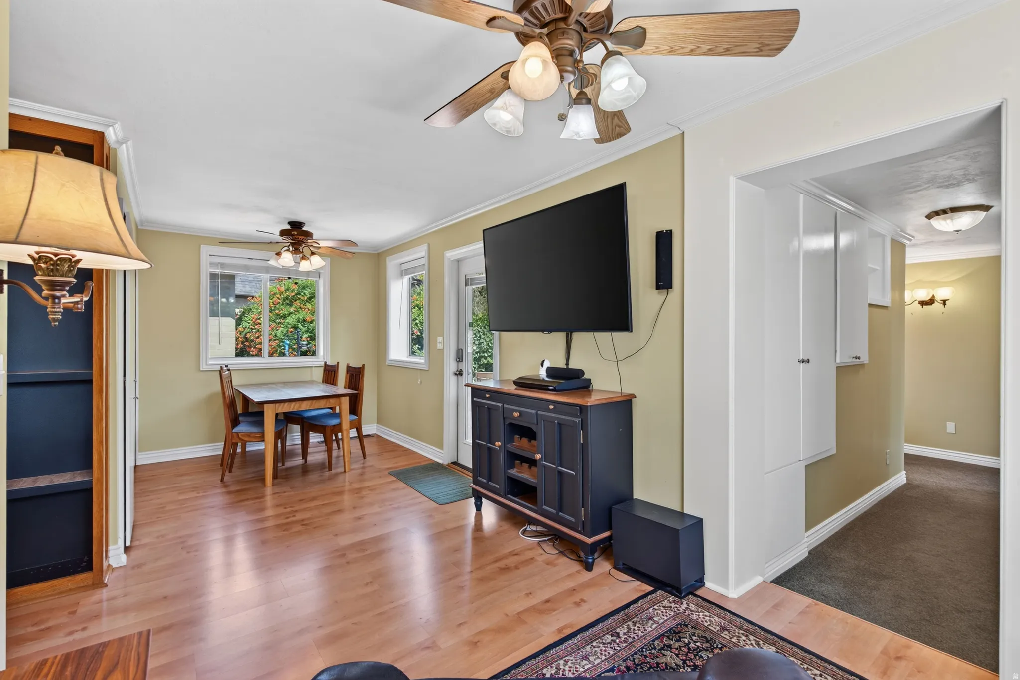 Expansive living area with wood-finish flooring, two ceiling fans, and an exterior access door