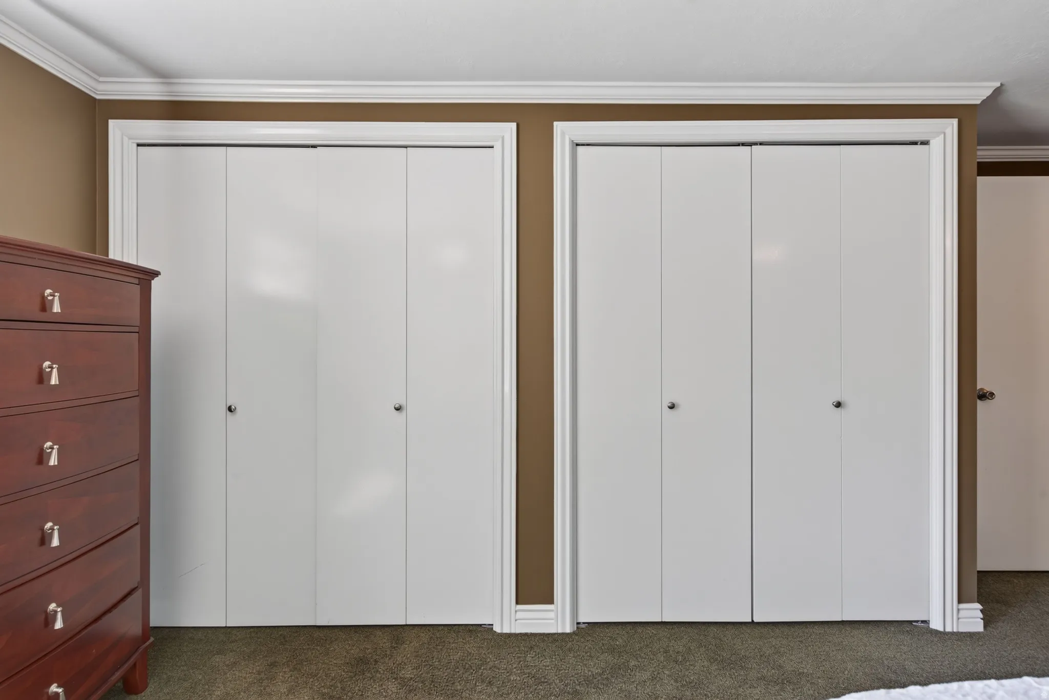 Two bi-fold closet doors with white trim and hardware