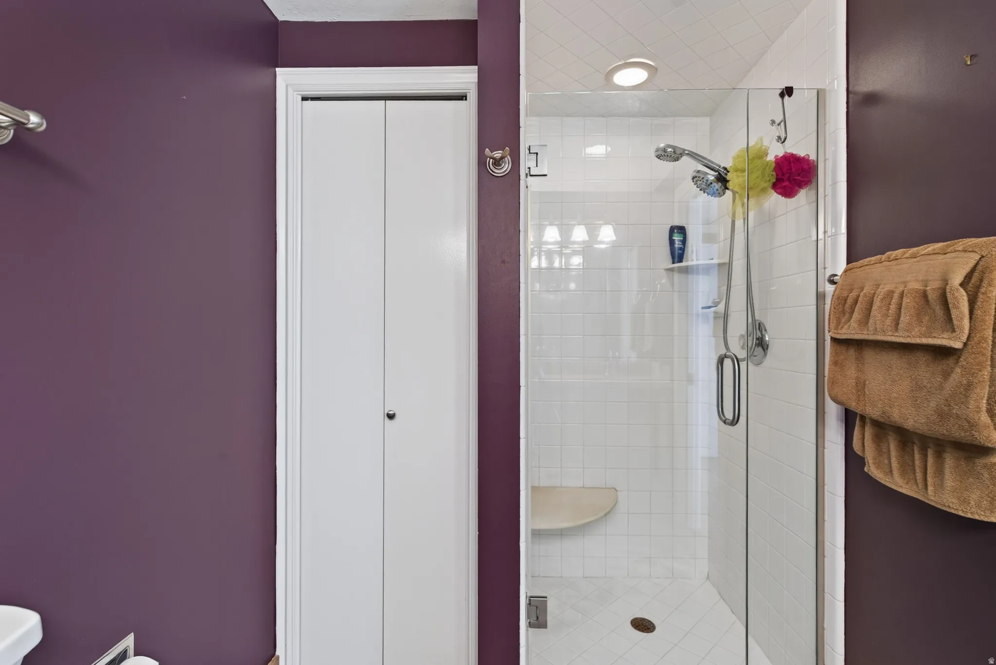 Glass-enclosed shower with white subway tile, integrated shower bench, and recessed lighting
