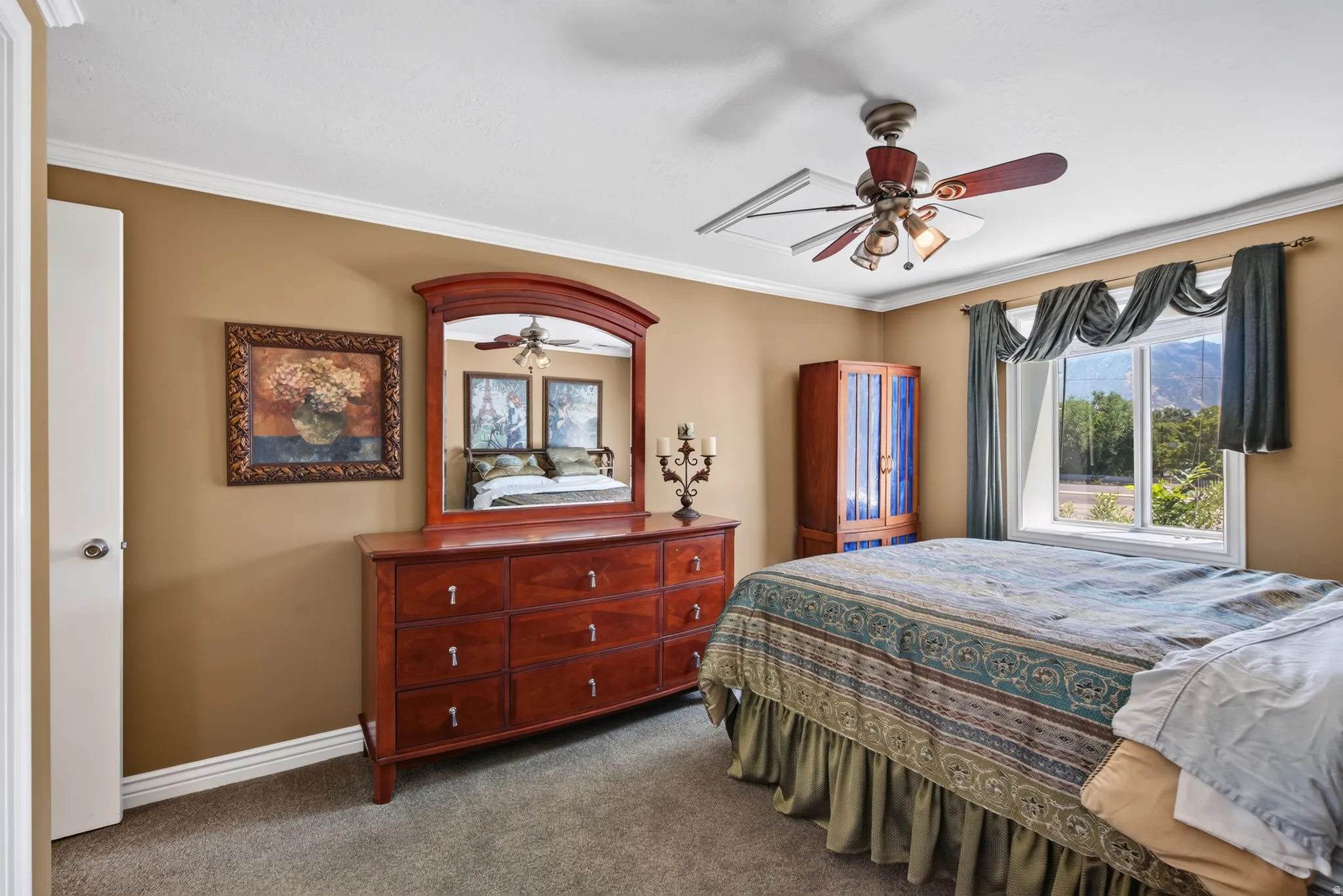 Bedroom featuring a window with exterior mountain scenery, crown molding, a ceiling fan with integrated lighting, a built-in closet, and carpet flooring