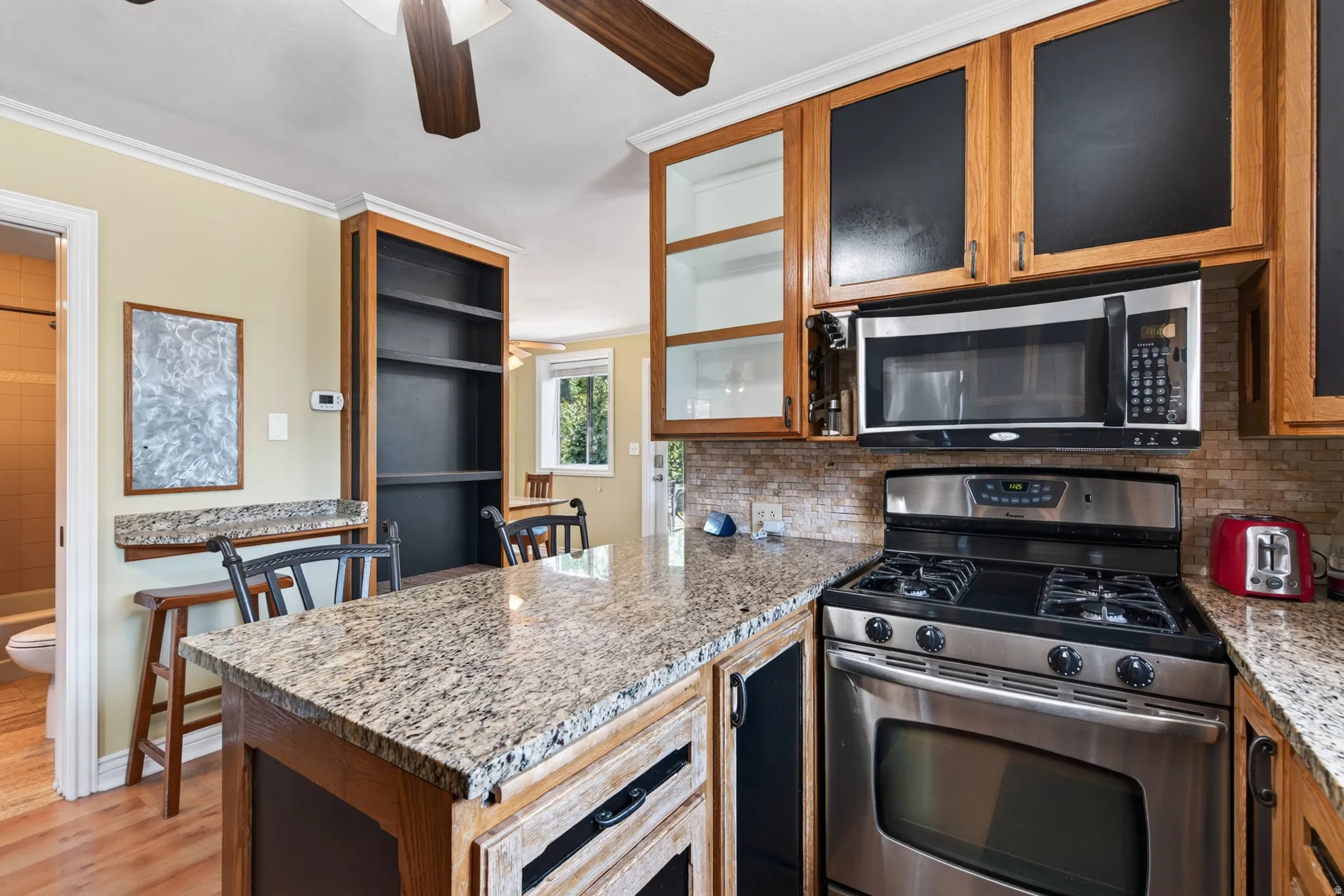 Kitchen featuring granite countertops, wood cabinetry, stainless steel range, and built-in microwave