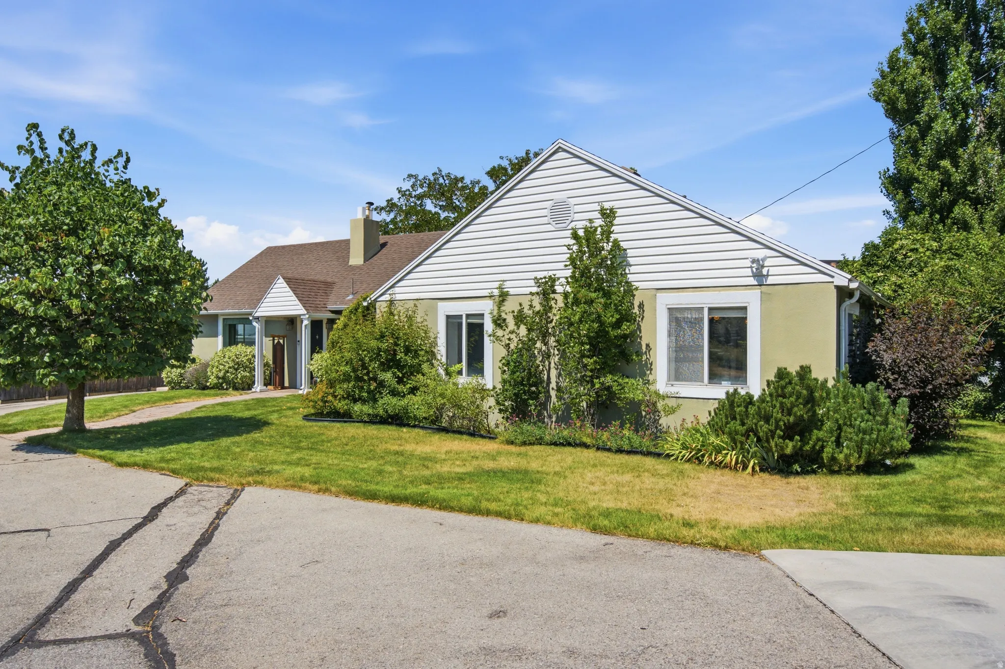 Exterior featuring light green siding with white trim, a brown shingle roof, and a prominent front entry with white columns