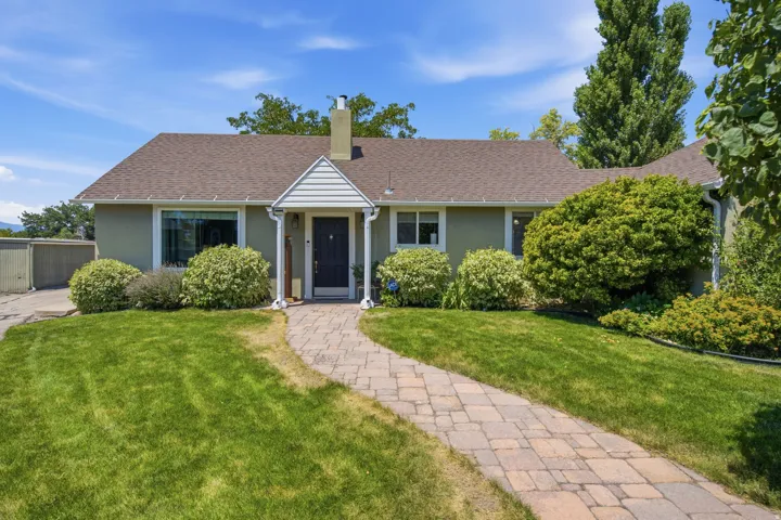 Stucco exterior with a peaked entry porch, framed by a paver stone walkway