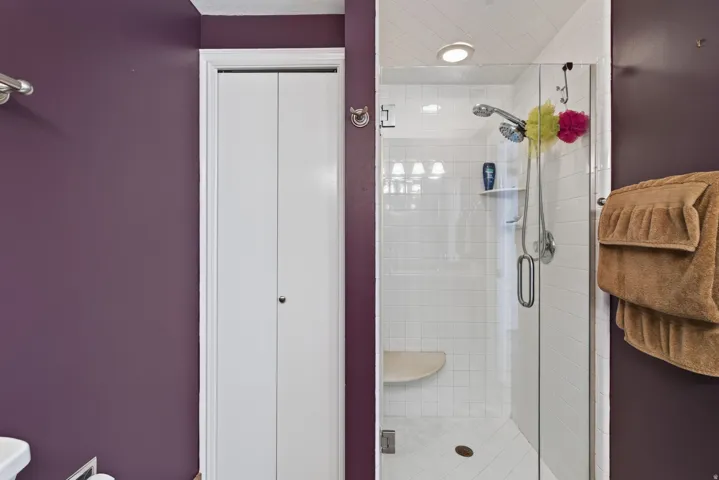 Glass-enclosed shower with white subway tile, integrated shower bench, and recessed lighting
