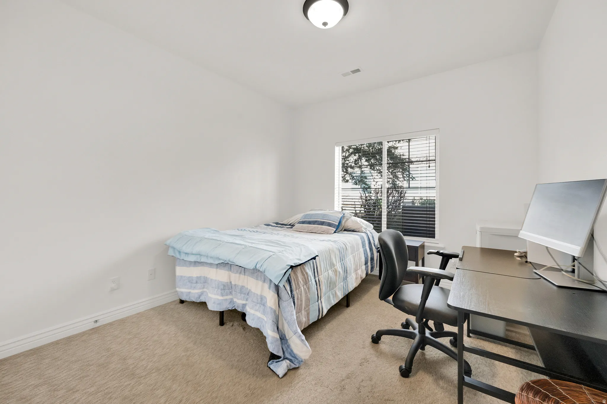 Bright room featuring a window with horizontal blinds, neutral carpeting, white walls, and a flush-mount ceiling light