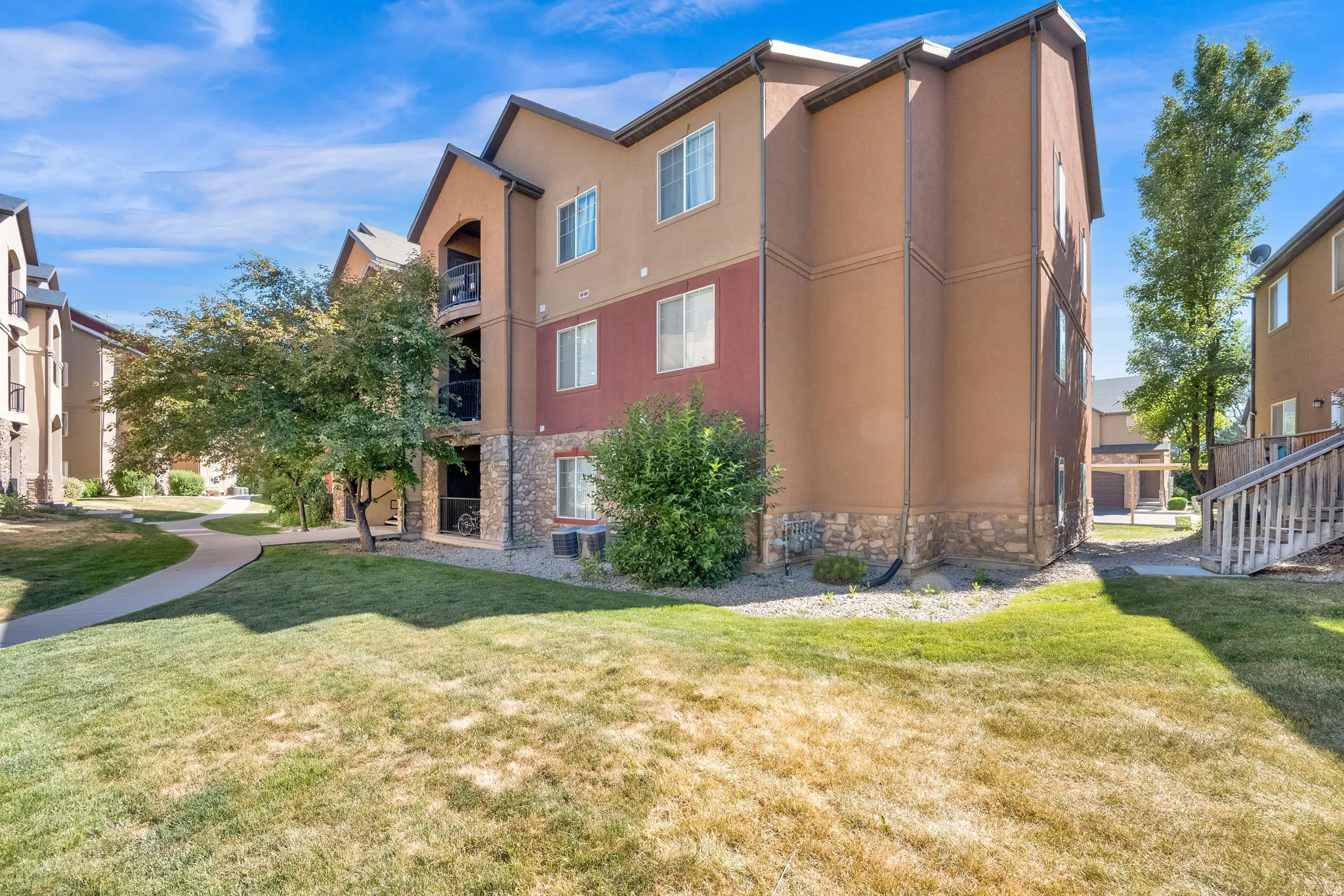 Multi-story exterior featuring a mix of stucco and stone veneer siding