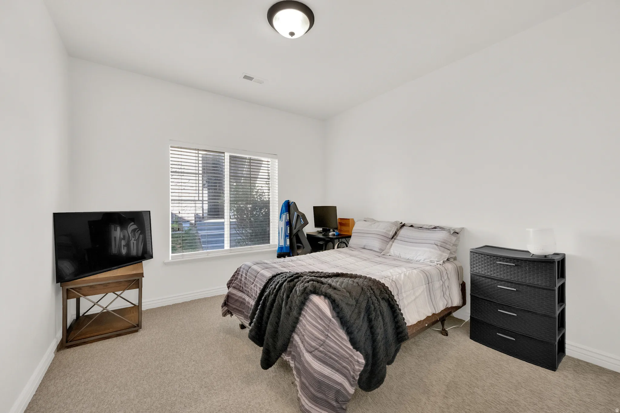 Carpeted room featuring a window with blinds, white walls, and a ceiling-mounted light fixture