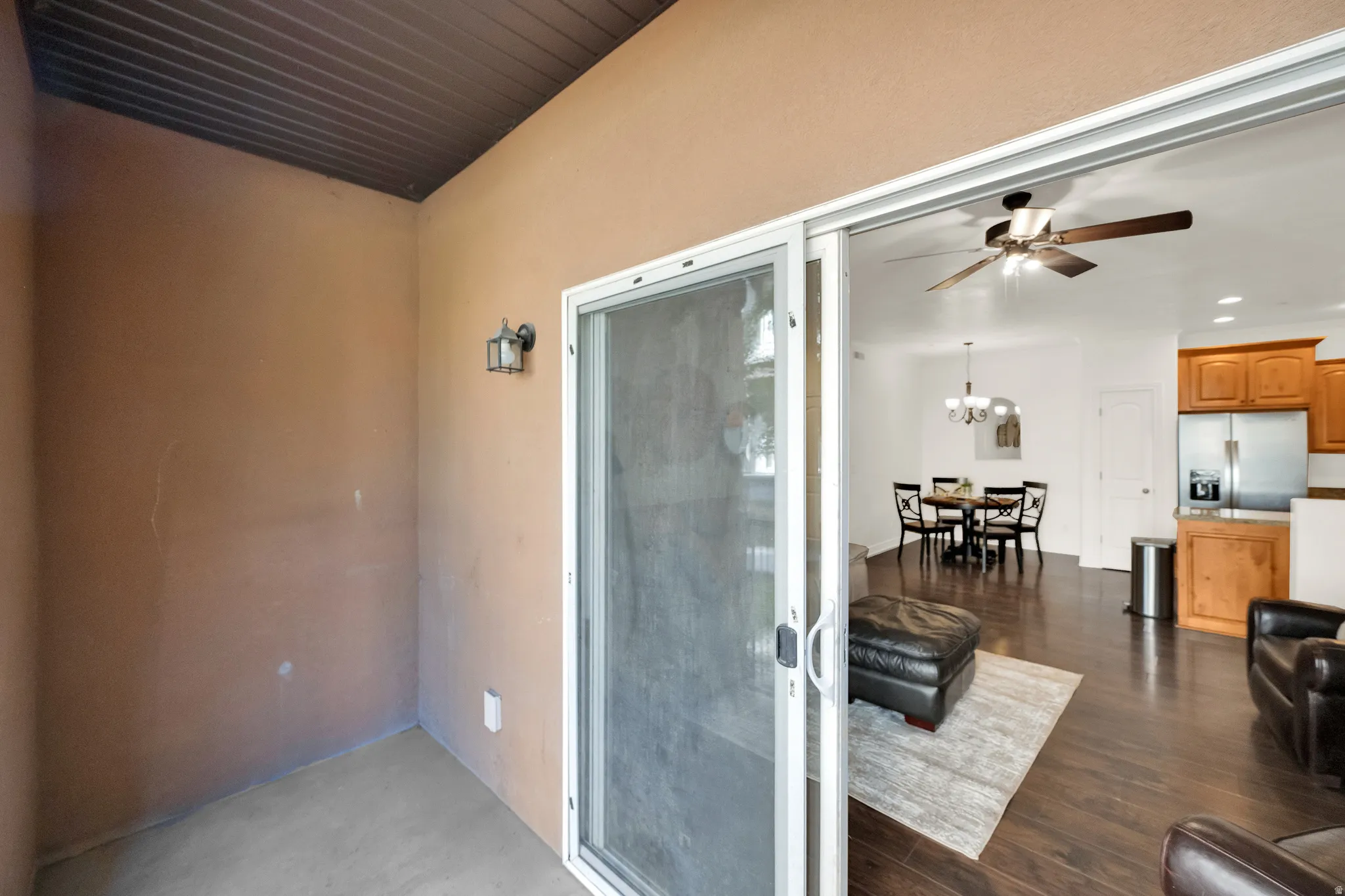 Sliding glass door opening to an outdoor patio with a corrugated ceiling and sconce lighting