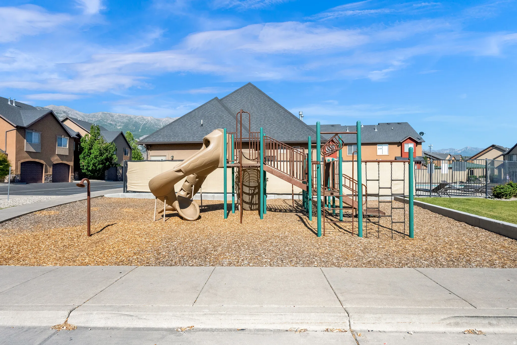 Community playground featuring a slide, climbing structures, and wood chip surfacing