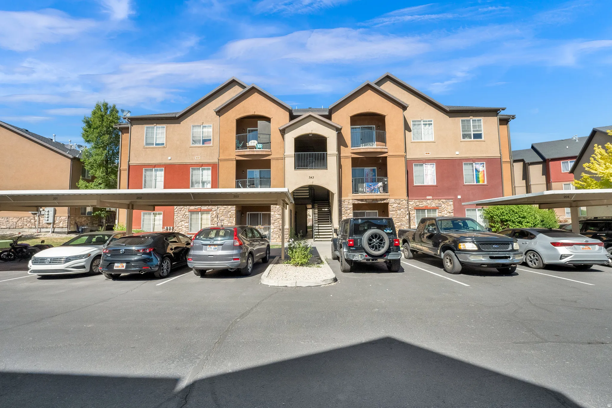 Multi-story residential building featuring a stucco and stone exterior with individual balconies