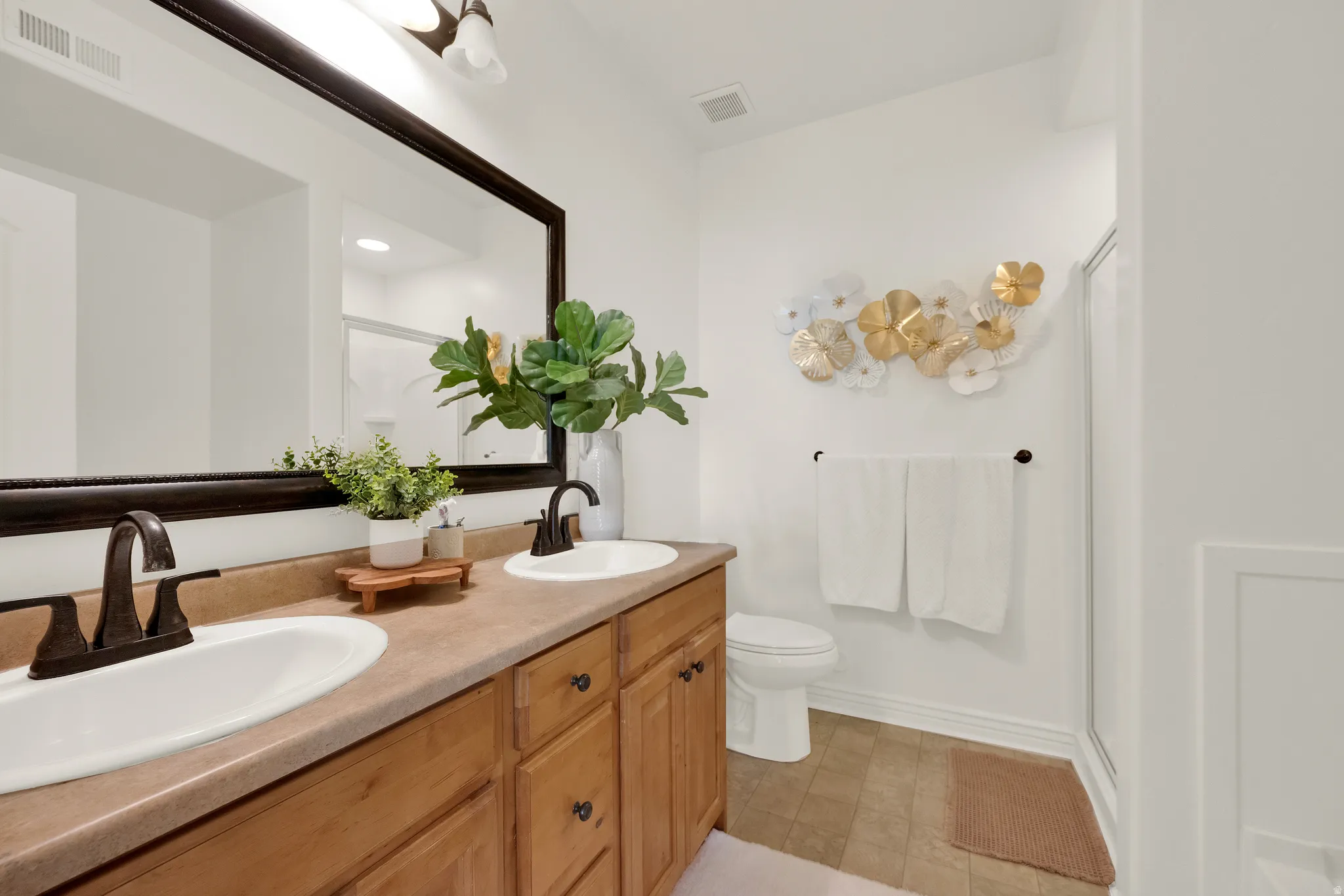 Dual white oval sinks set in a light brown countertop with a wooden vanity