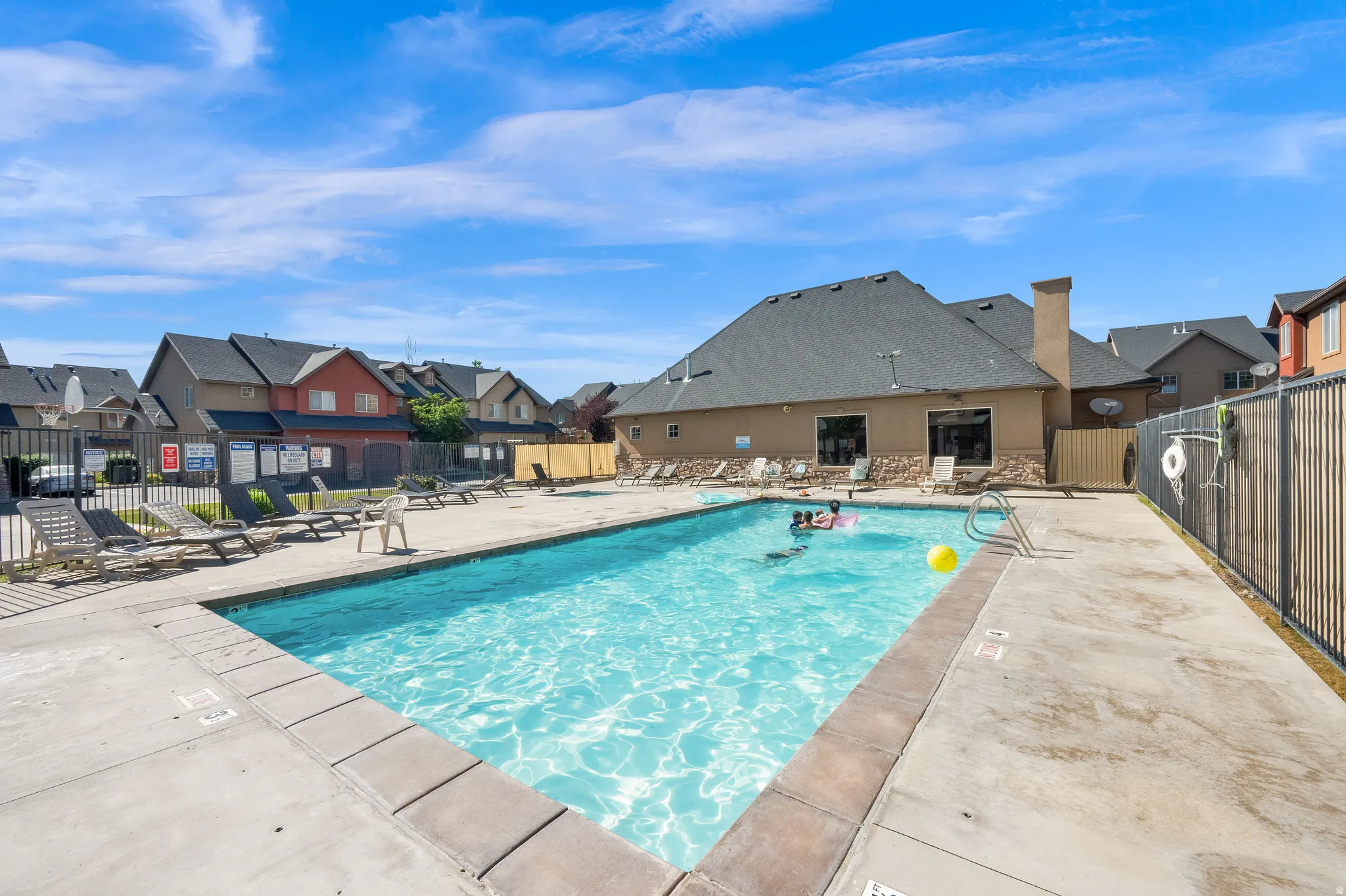 Community swimming pool with concrete surround and metal perimeter fencing
