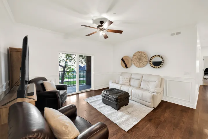 Spacious living area featuring wood-finish flooring, white panel molding, and crown molding
