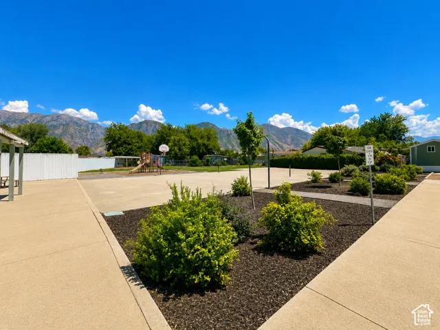 Paved outdoor recreational area featuring a basketball hoop and playground equipment
