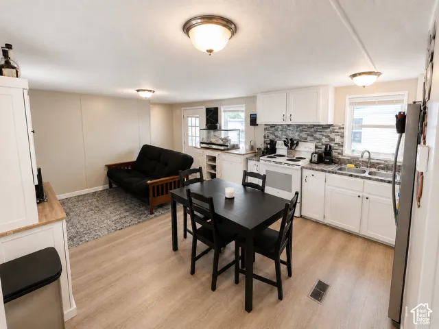 Open-concept living area featuring wood-finish flooring, white cabinetry with dark hardware, a tile backsplash, and a double basin sink
