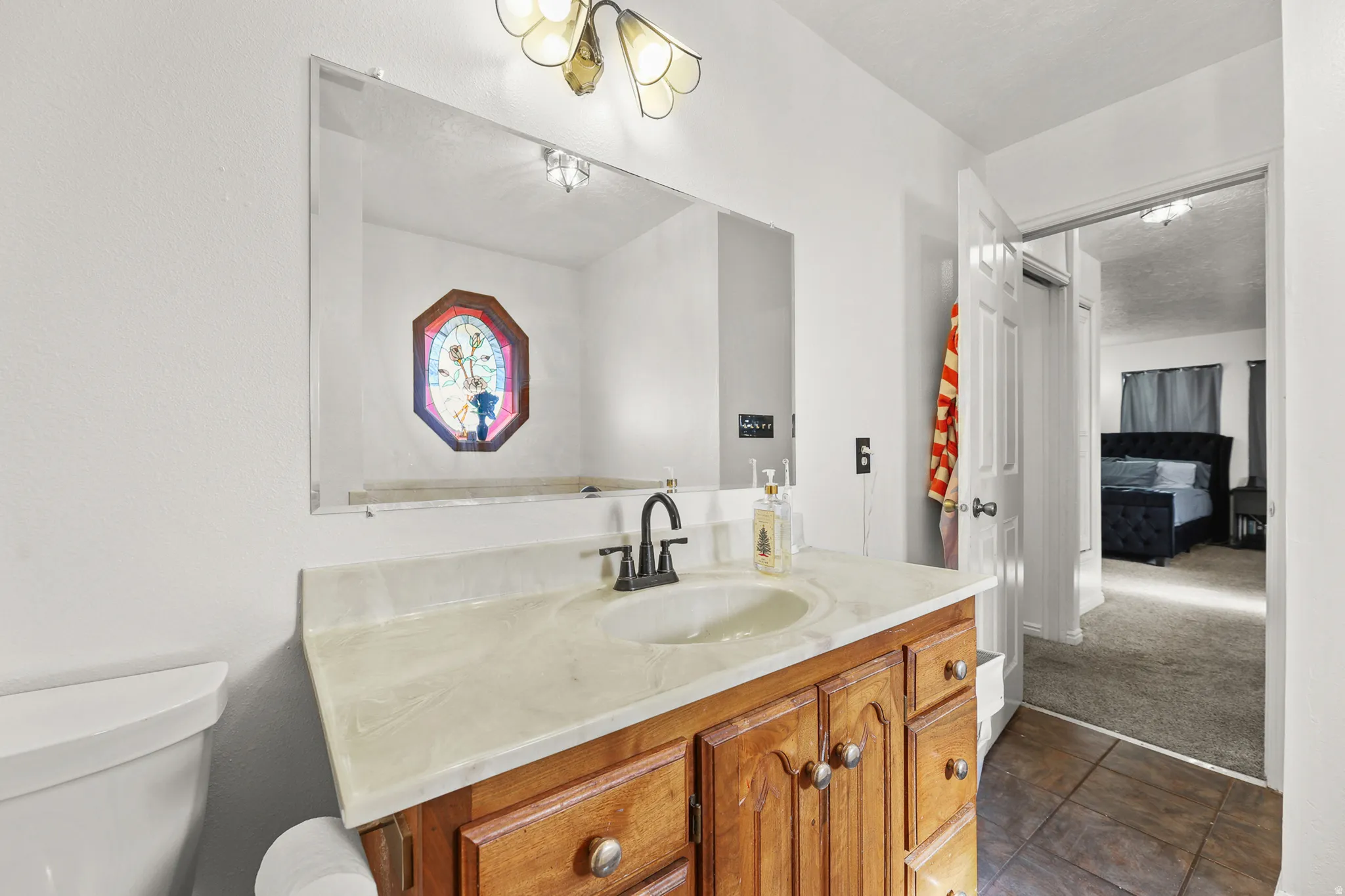 Bathroom vanity featuring a light-toned countertop, integrated sink, and wood cabinetry