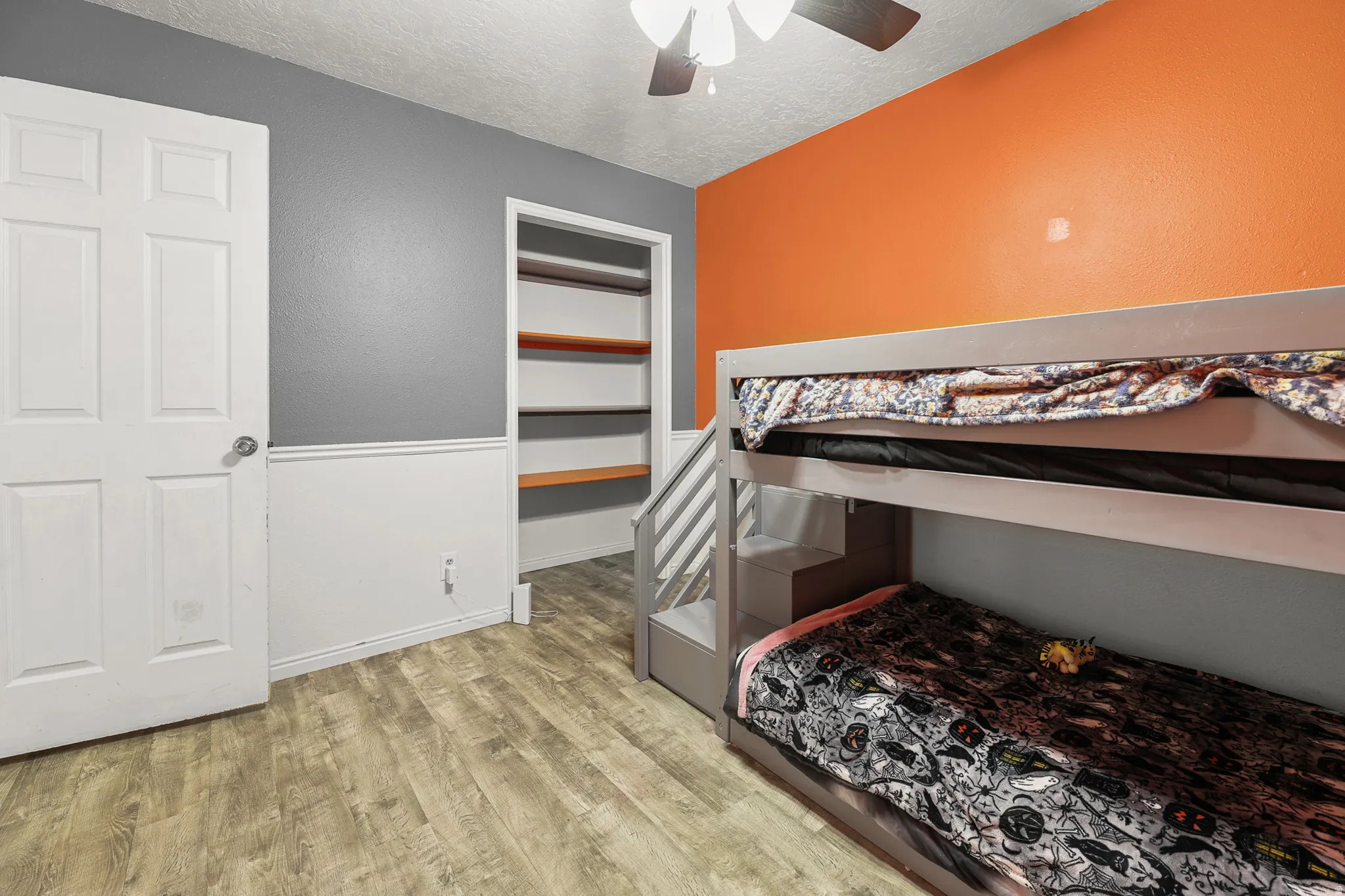 Interior room featuring wood-finish flooring, a white paneled door, and a built-in shelving unit with wood shelves