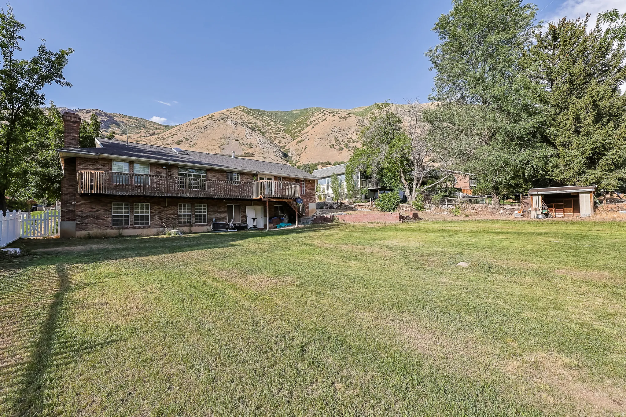 Expansive lawn with mountain backdrop, featuring a brick exterior, two levels of windows, and an upper-level balcony
