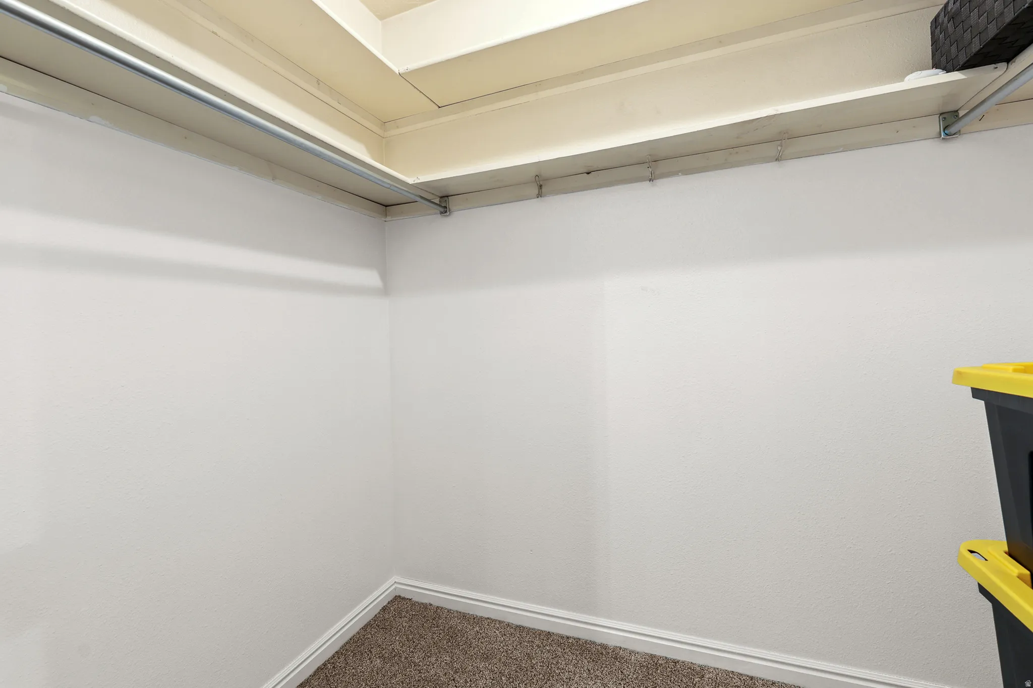 Interior closet featuring white painted walls and a single metal hanging rod