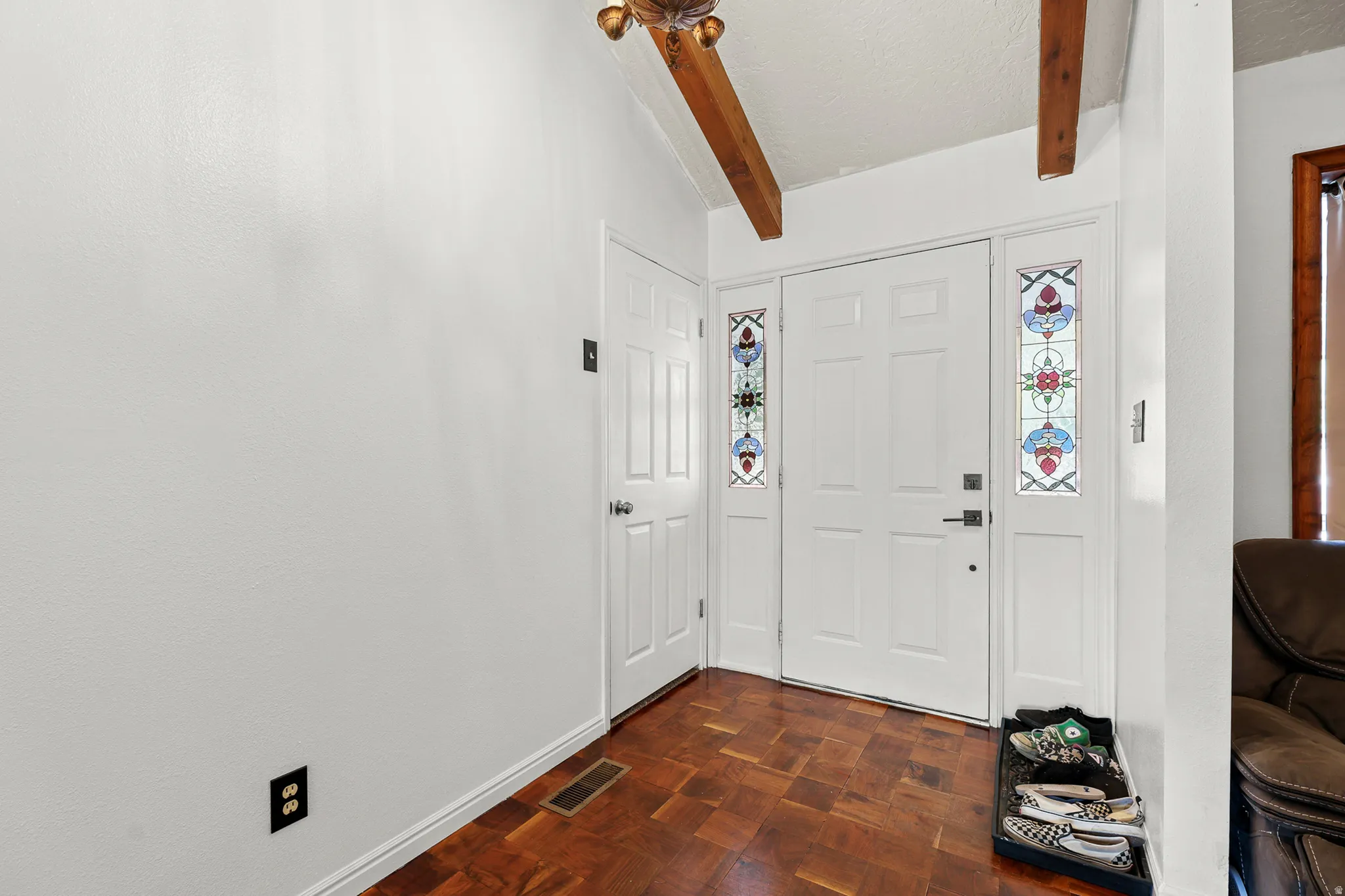 Entryway featuring a paneled door with decorative glass sidelights, wood-finish flooring, and exposed wood ceiling beams