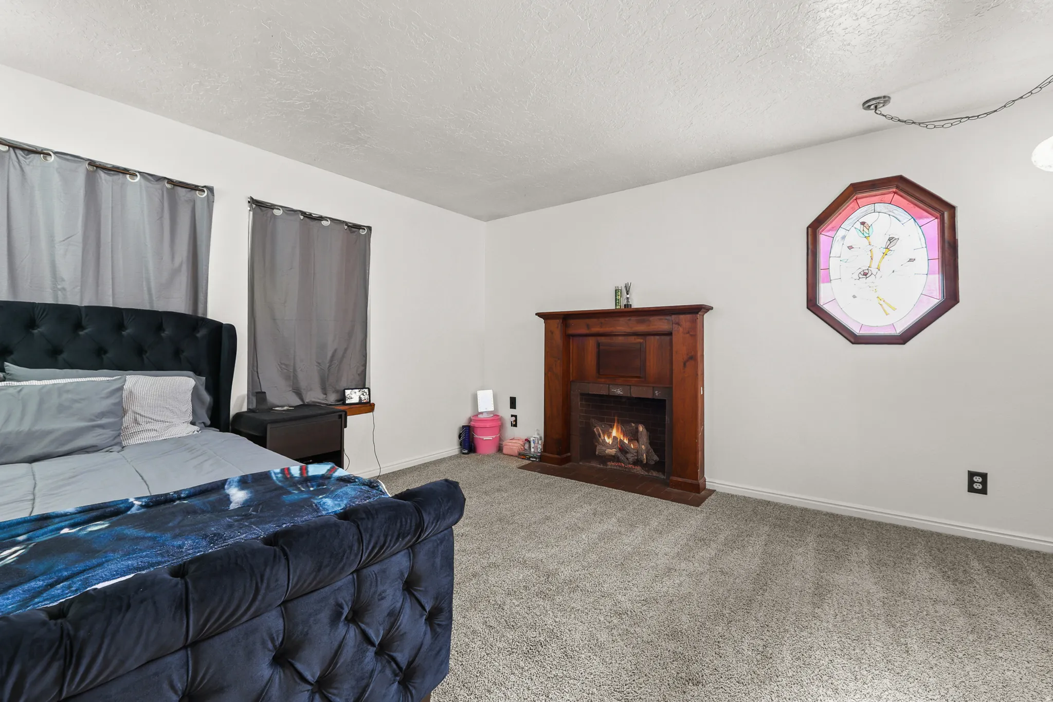 Interior featuring a wood-surround fireplace, an octagonal stained-glass window, and light-colored carpeting