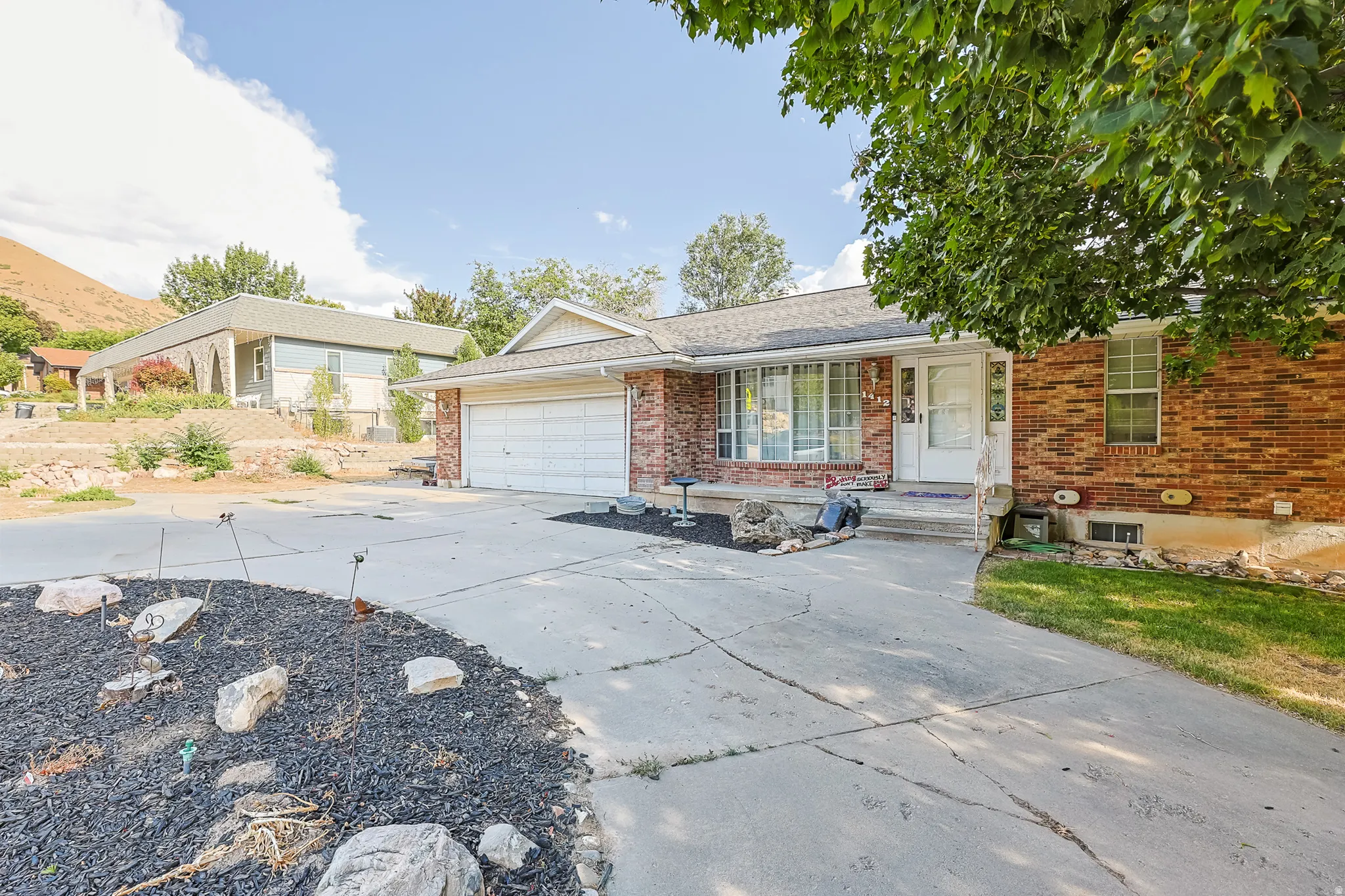 Brick facade home featuring a two-car garage, concrete driveway, and front entryway