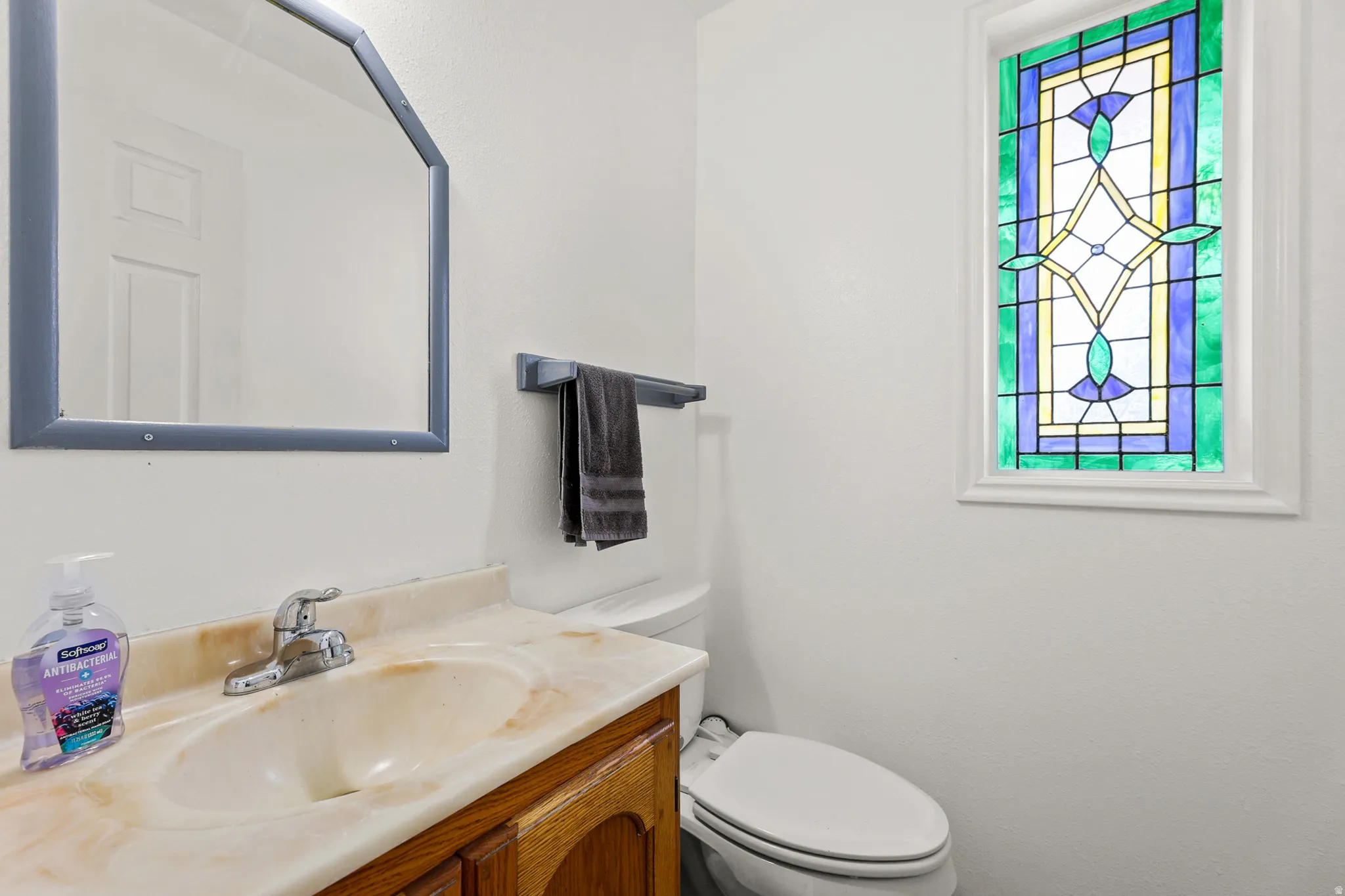 Bathroom featuring a stained glass window, vanity with a built-in sink, and a framed mirror