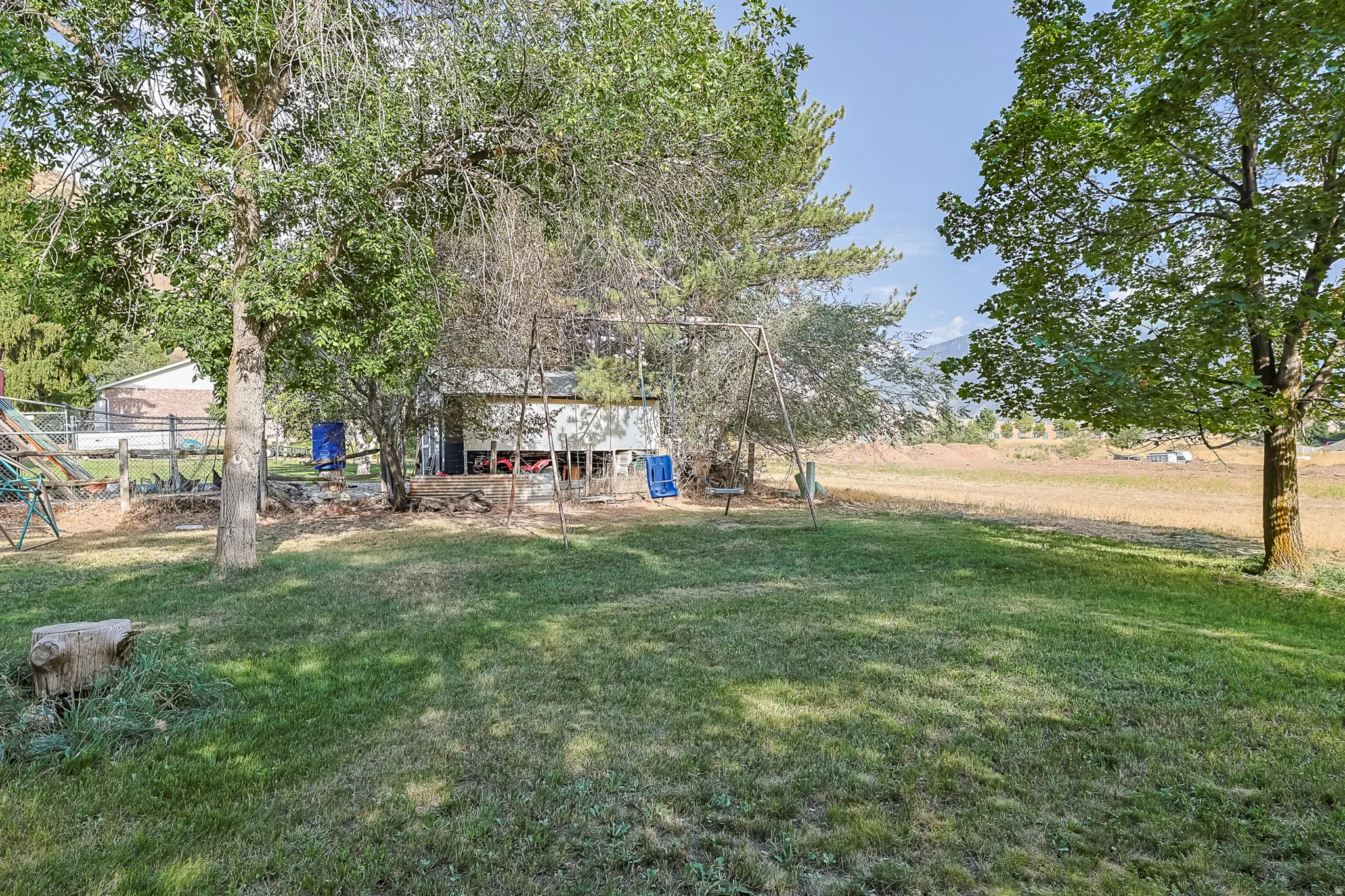 Expansive grassy yard featuring mature trees and a distant mountainous landscape