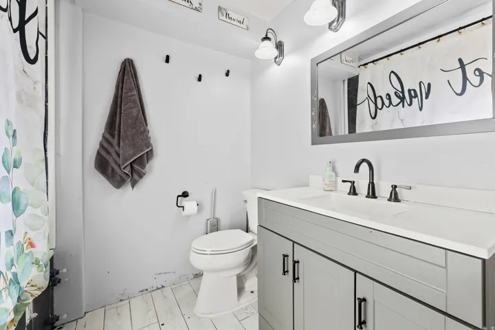 Bathroom featuring a white vanity with a light gray cabinet base, an integrated sink, and a matte black faucet