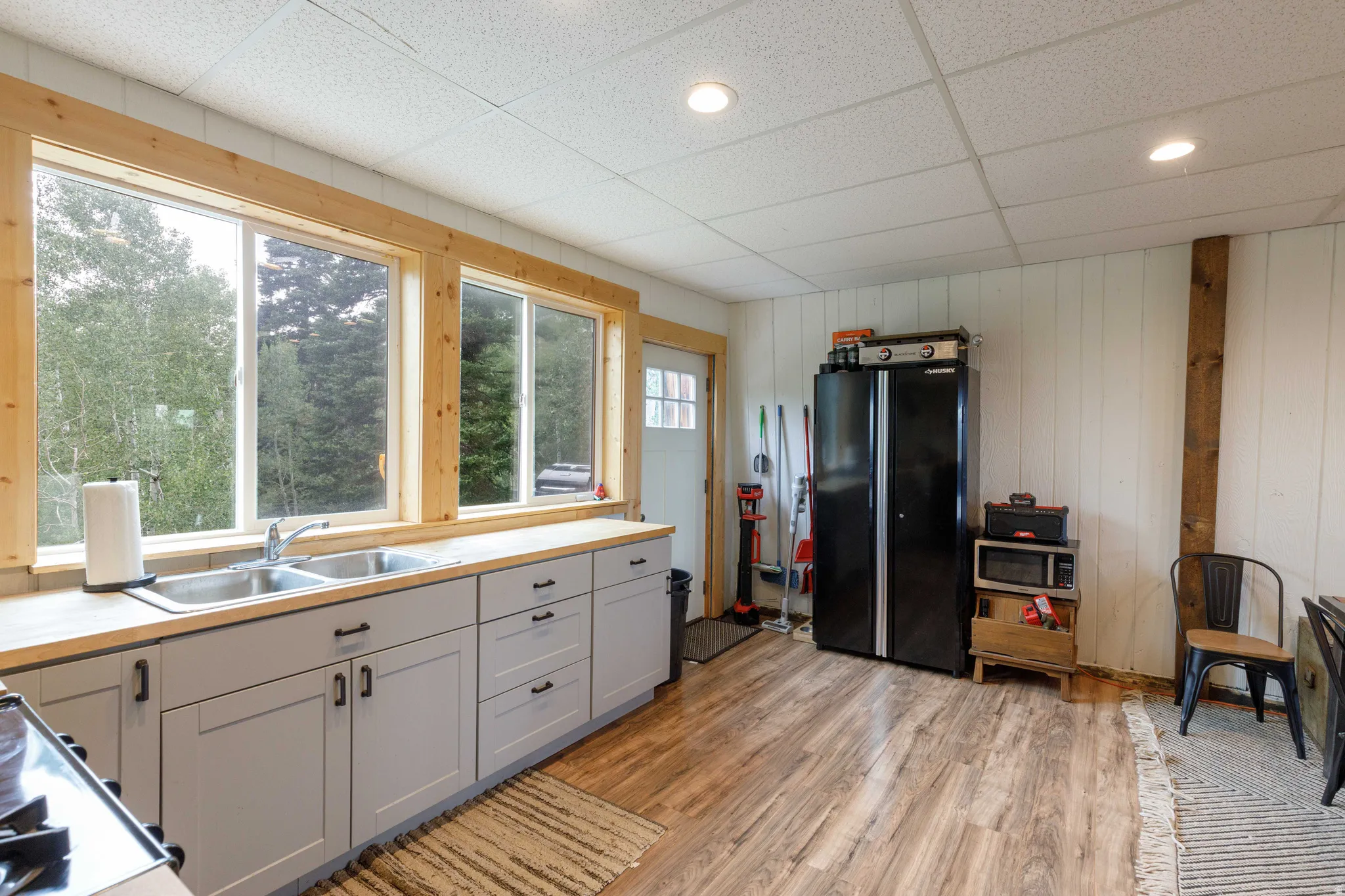 Kitchen area featuring light wood-finish countertops and light gray cabinetry with dark hardware