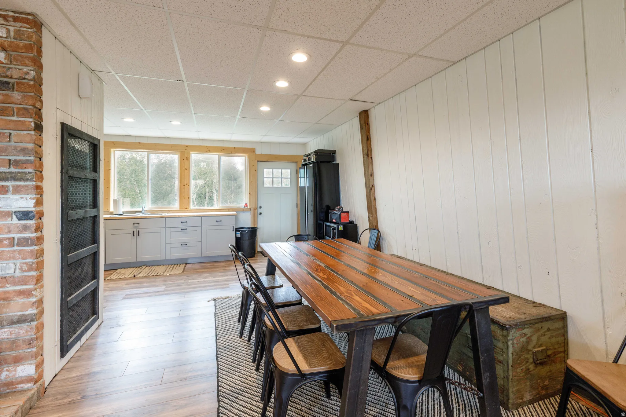 Open-concept dining and kitchen area featuring wood-finish flooring, recessed lighting, and white paneled walls