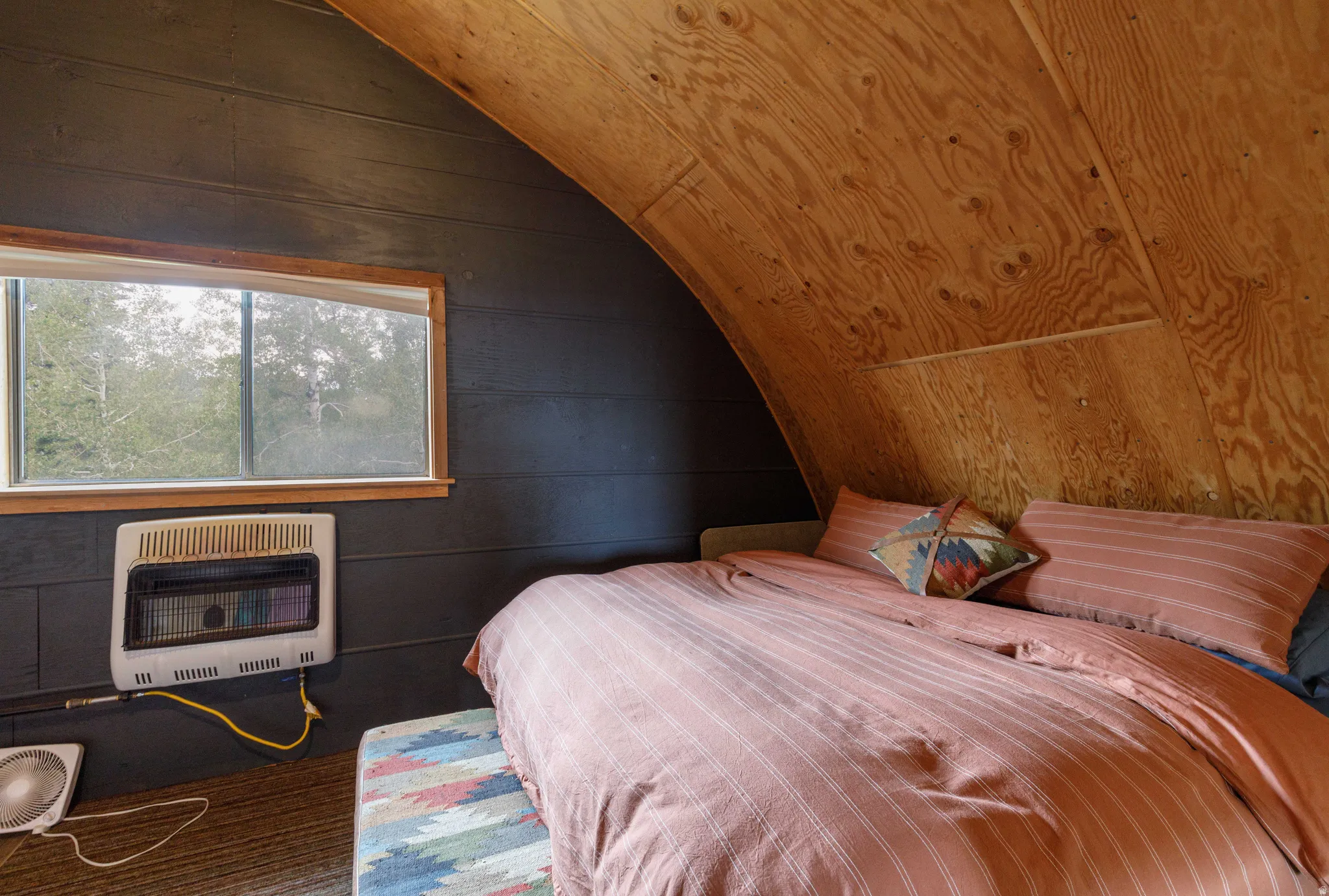 Room featuring an arched wood-finish ceiling, dark paneled walls, and a window with wood-finish trim