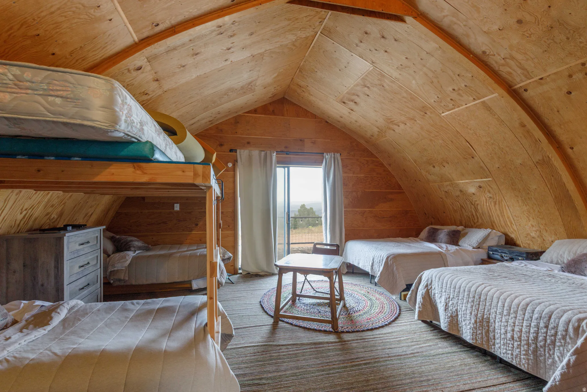 Vaulted wood-paneled ceiling with exposed wood beams, wood-finish flooring, and sliding glass doors