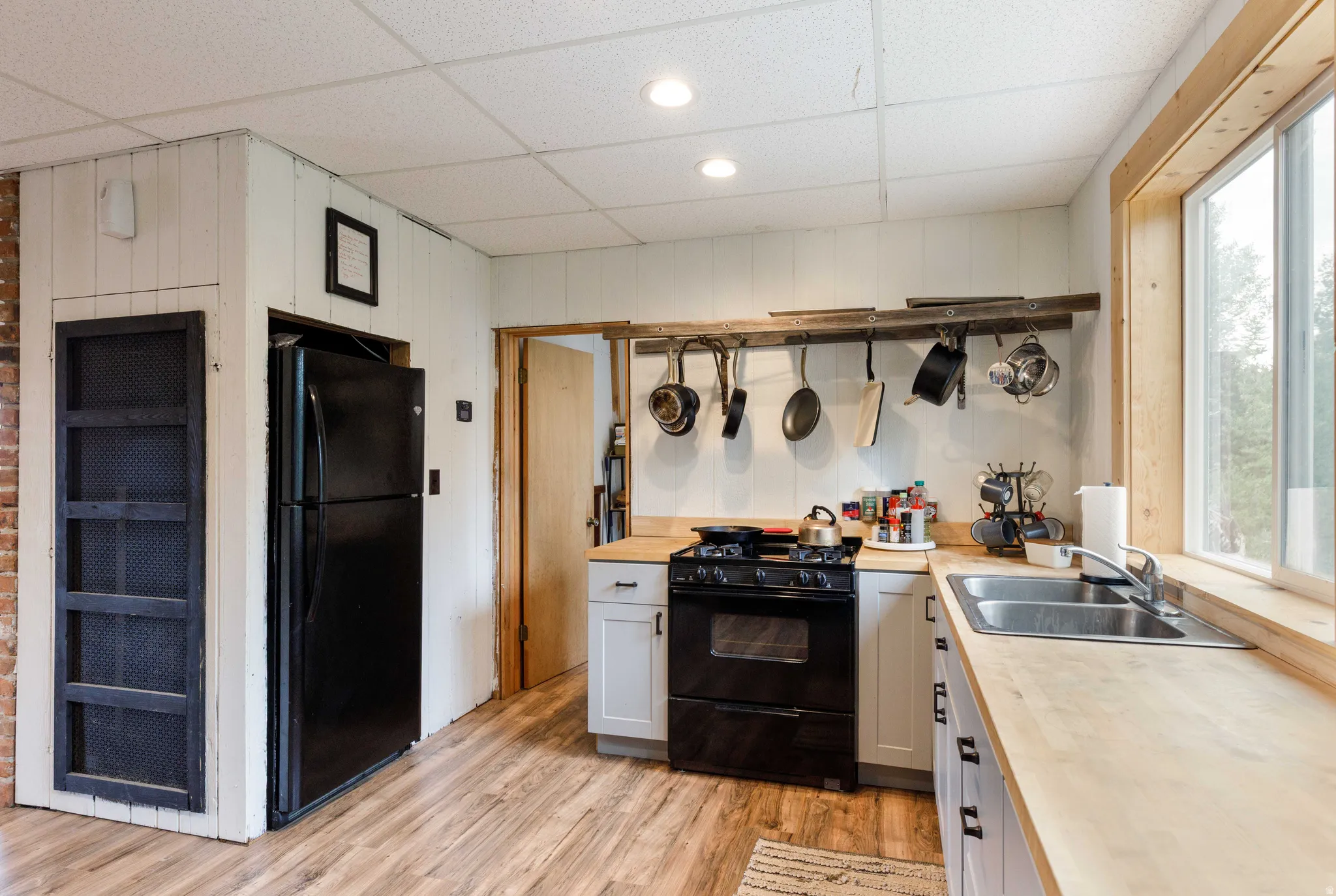 Kitchen featuring wood-finish flooring, light wood countertops, white paneled walls, and a recessed ceiling