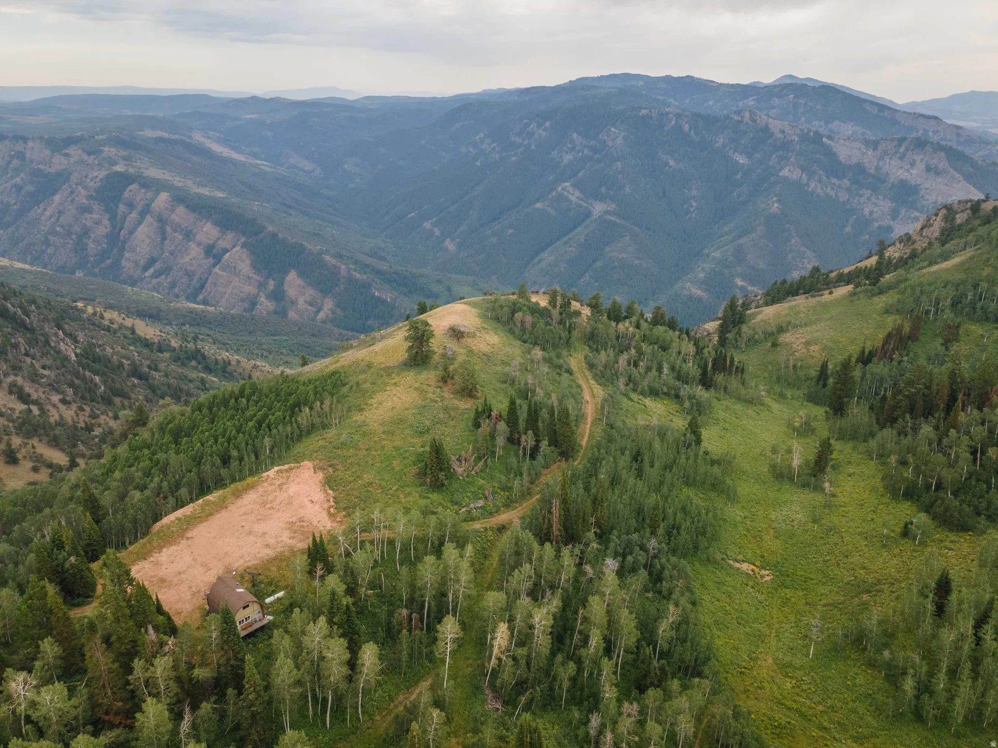 Mountainous terrain with extensive tree coverage and a partially cleared area