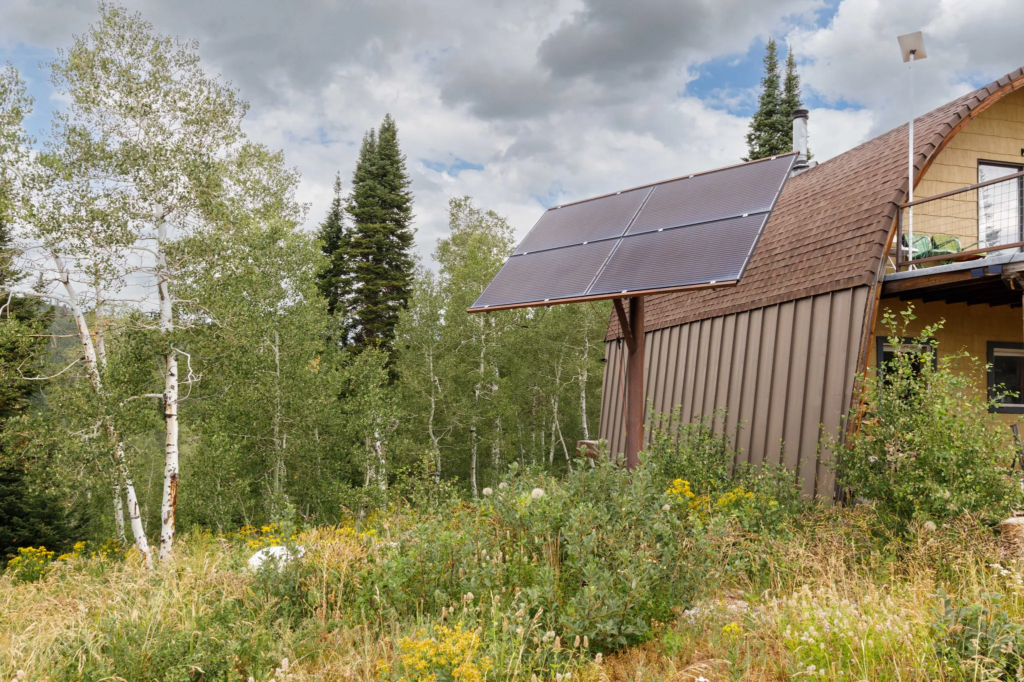Property exterior featuring a rustic A-frame design, brown shingle roofing, and vertical siding