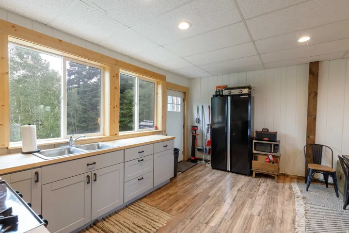 Kitchen area featuring light wood-finish countertops and light gray cabinetry with dark hardware