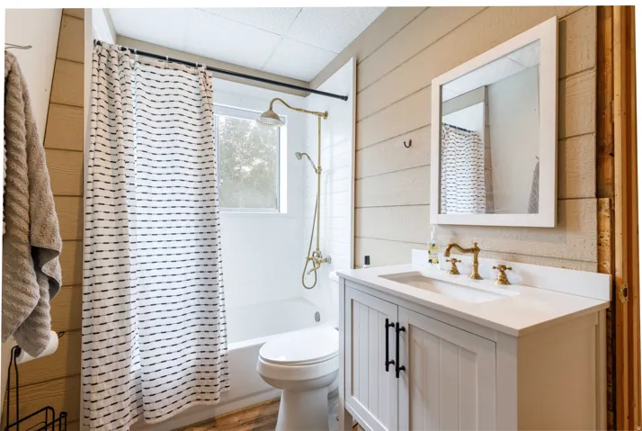 Bathroom featuring a white vanity with a rectangular basin sink, brass-finish faucet, and coordinating framed mirror