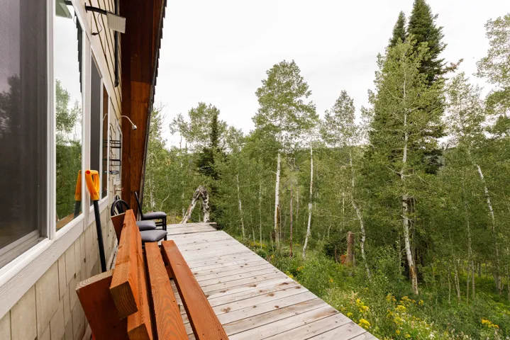 Expansive wood deck with a natural wood finish, bordered by a beige exterior wall with large windows